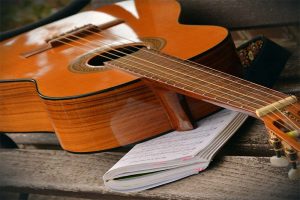 Acoustic guitar and sheet music book outside